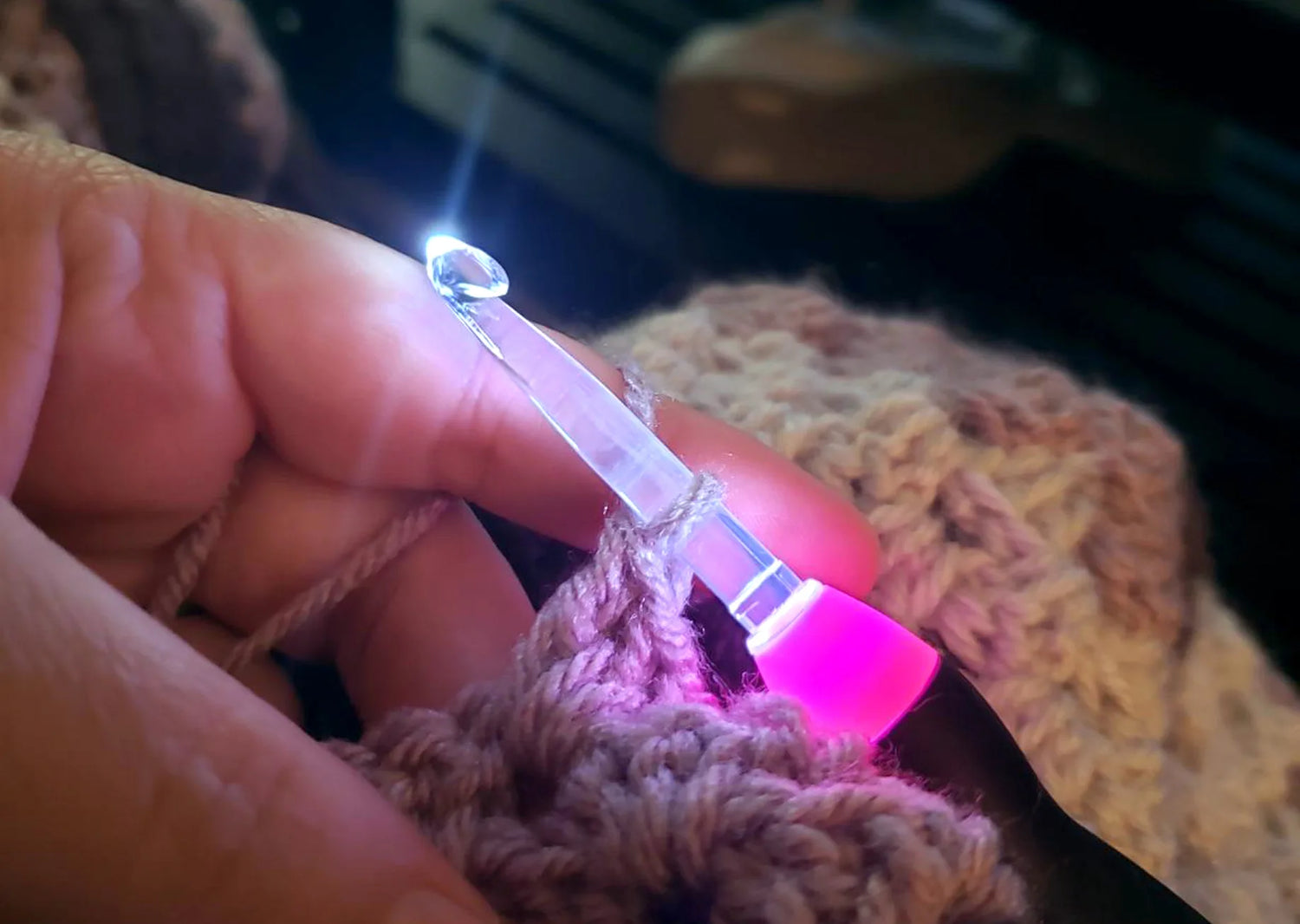 Soft pink-glow crochet hook stitching brown yarn, creating a relaxing, cozy atmosphere for stress-free evening crocheting.